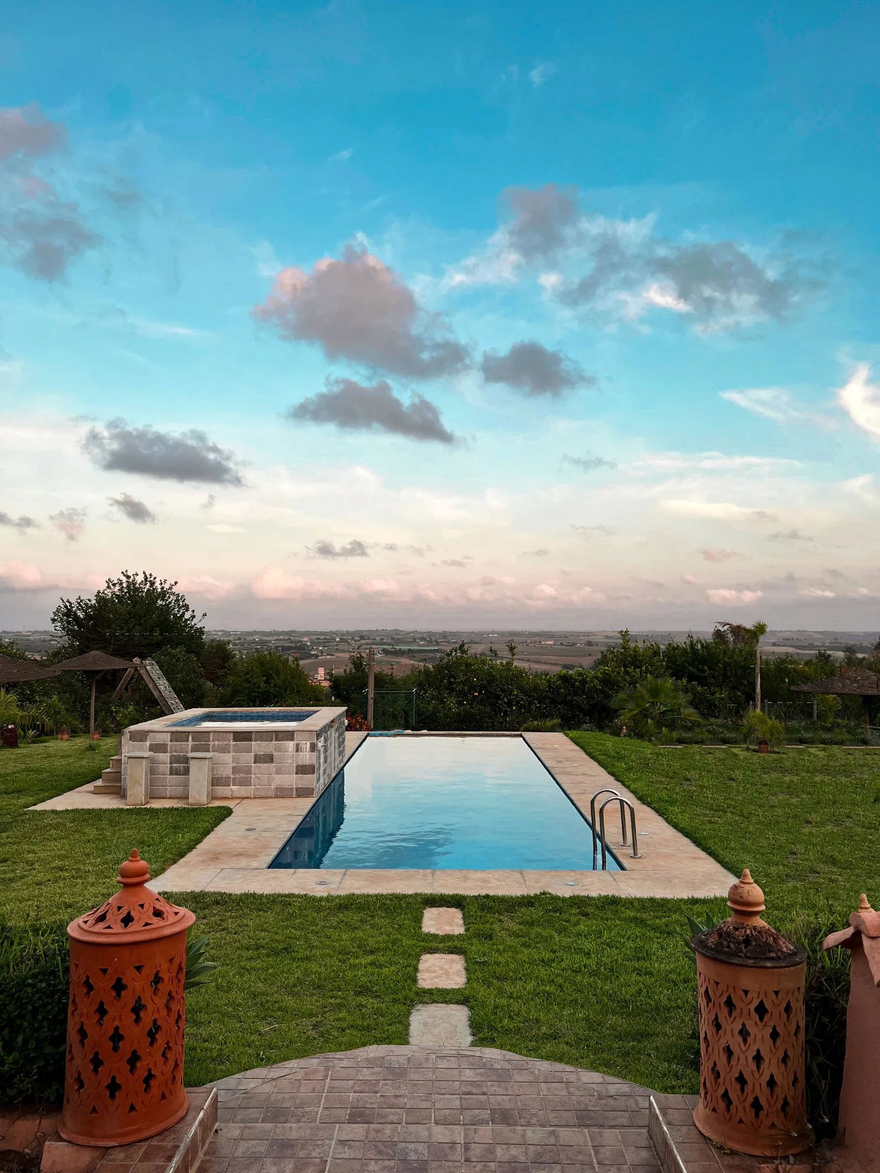 Piscine extérieure bordée de végétation au coucher du soleil